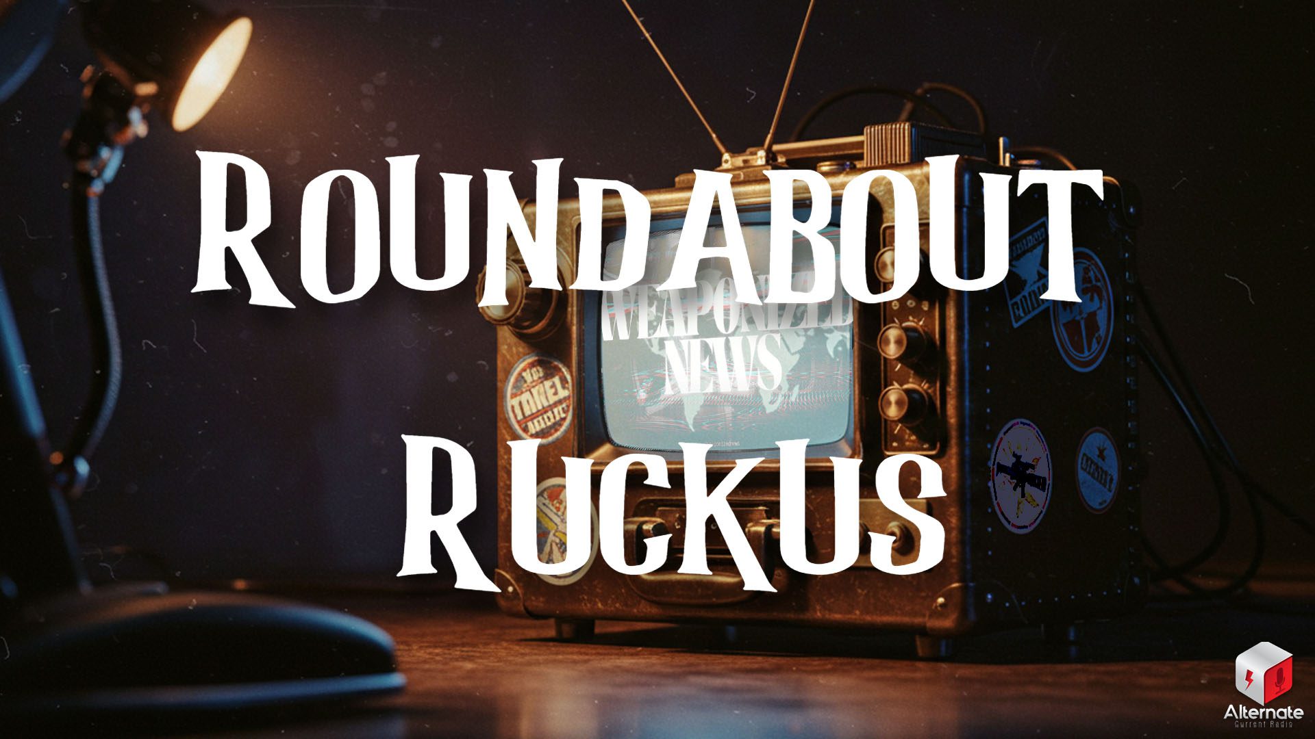 A vintage television decorated with travel-themed stickers and featuring a carrying handle, knobs and switches, and a set of rabbit ears antenna is being dimly lit by a desk lamp.